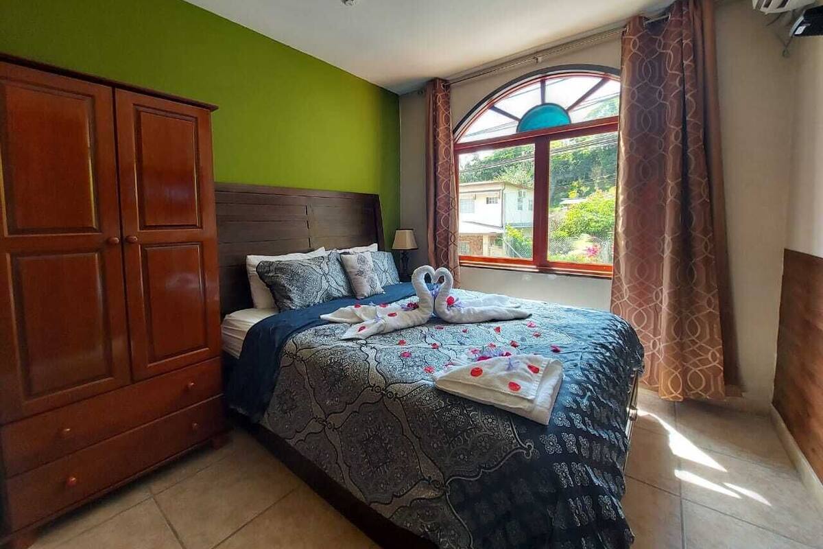 Une chambre à coucher avec un lit, une armoire en bois et une fenêtre avec des rideaux.