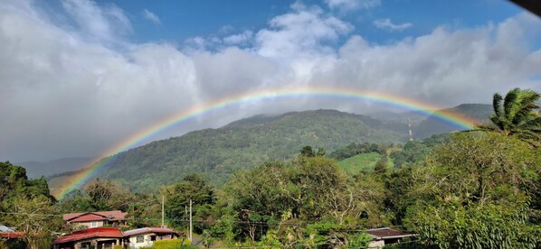 A lush green landscape with a mountain in the background and a rainbow arching across the sky. - La Casa de la Abuela (Boquete)