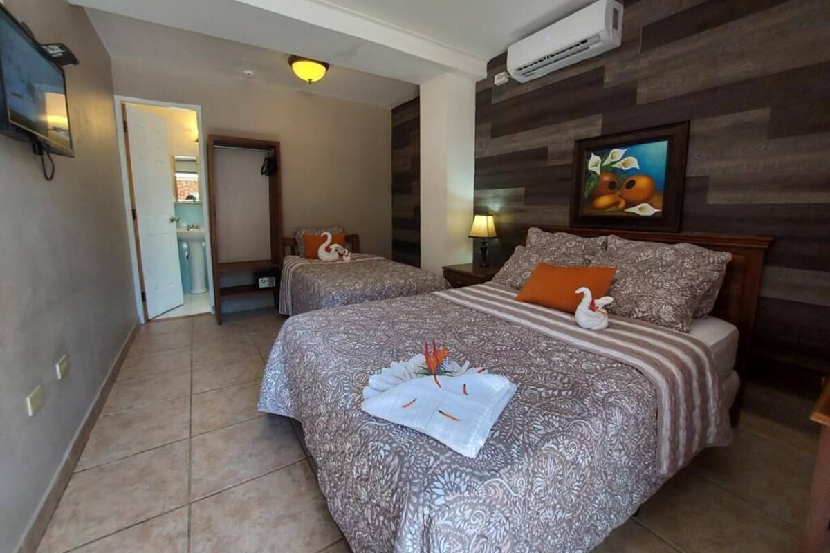 Une chambre d’hôtel avec deux lits, un tableau au mur et un appareil de climatisation.