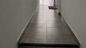 A long, narrow hallway with a tiled floor and white walls.