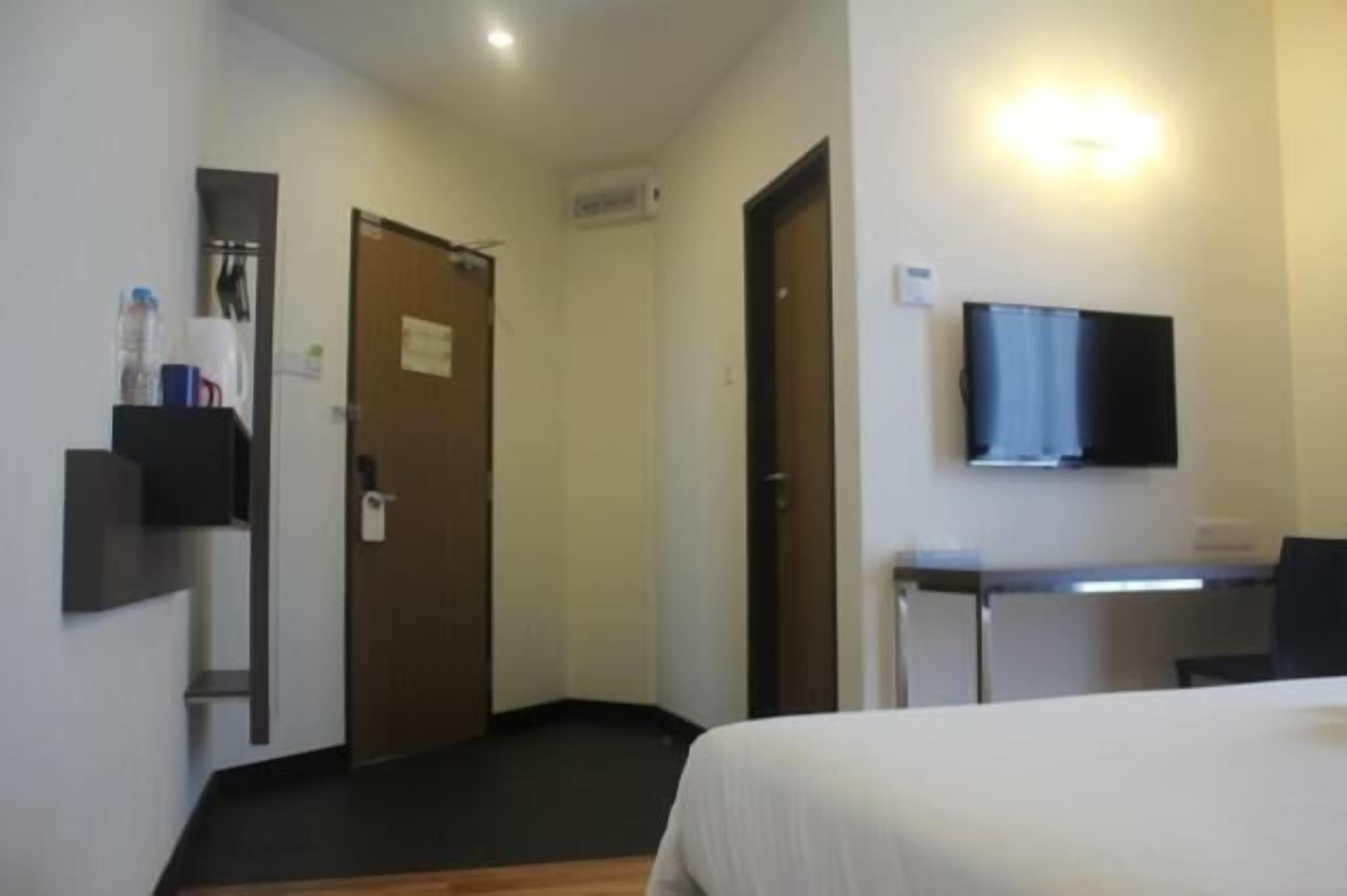 Una habitación de hotel con una cama, un escritorio, un televisor y una puerta.