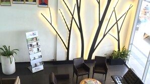 A modern lobby with dark leather sofas, a coffee table, and a reception desk. There are framed pictures on the wall and a potted plant near the reception. - Fuller Hotel (Alor Setar)