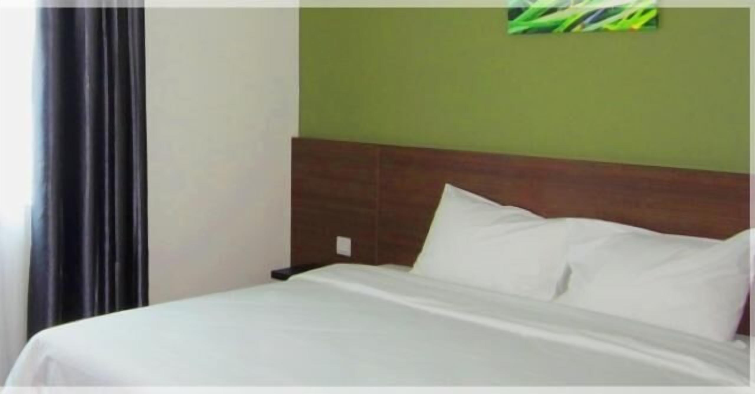 A hotel room with a bed, a nightstand, and a green wall.