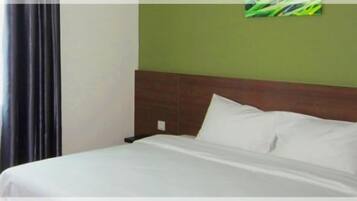 A hotel room with a bed, a nightstand, and a green wall.