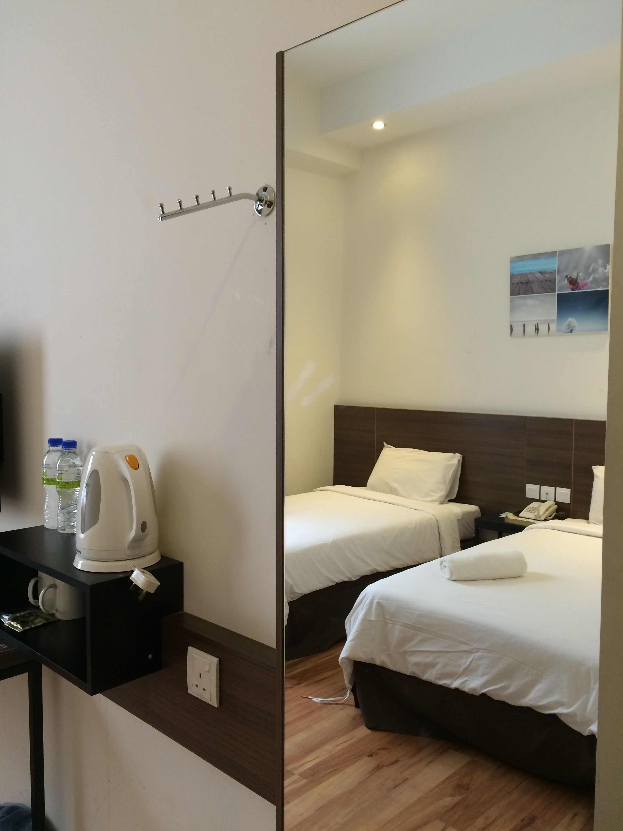 A hotel room with two beds, a coffee maker, and a small table with water bottles.
