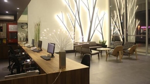 A modern reception area with a long desk, computers, and seating. - Fuller Hotel (Alor Setar)