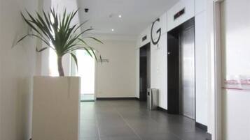 A modern hallway with a potted plant, a sign with the letter 'G', and an elevator.