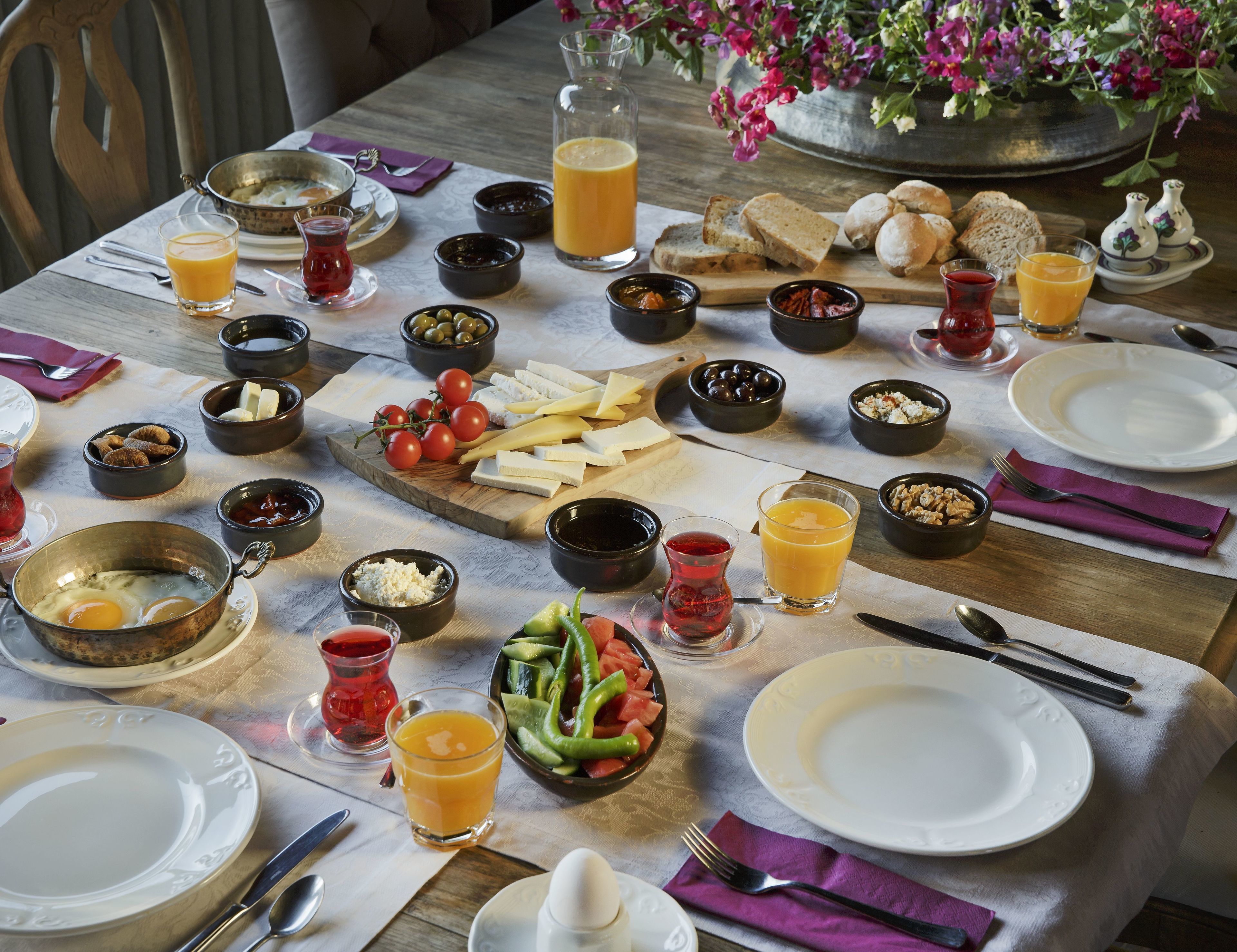 A breakfast table with various food items and drinks, including cheese, bread, and fruits.