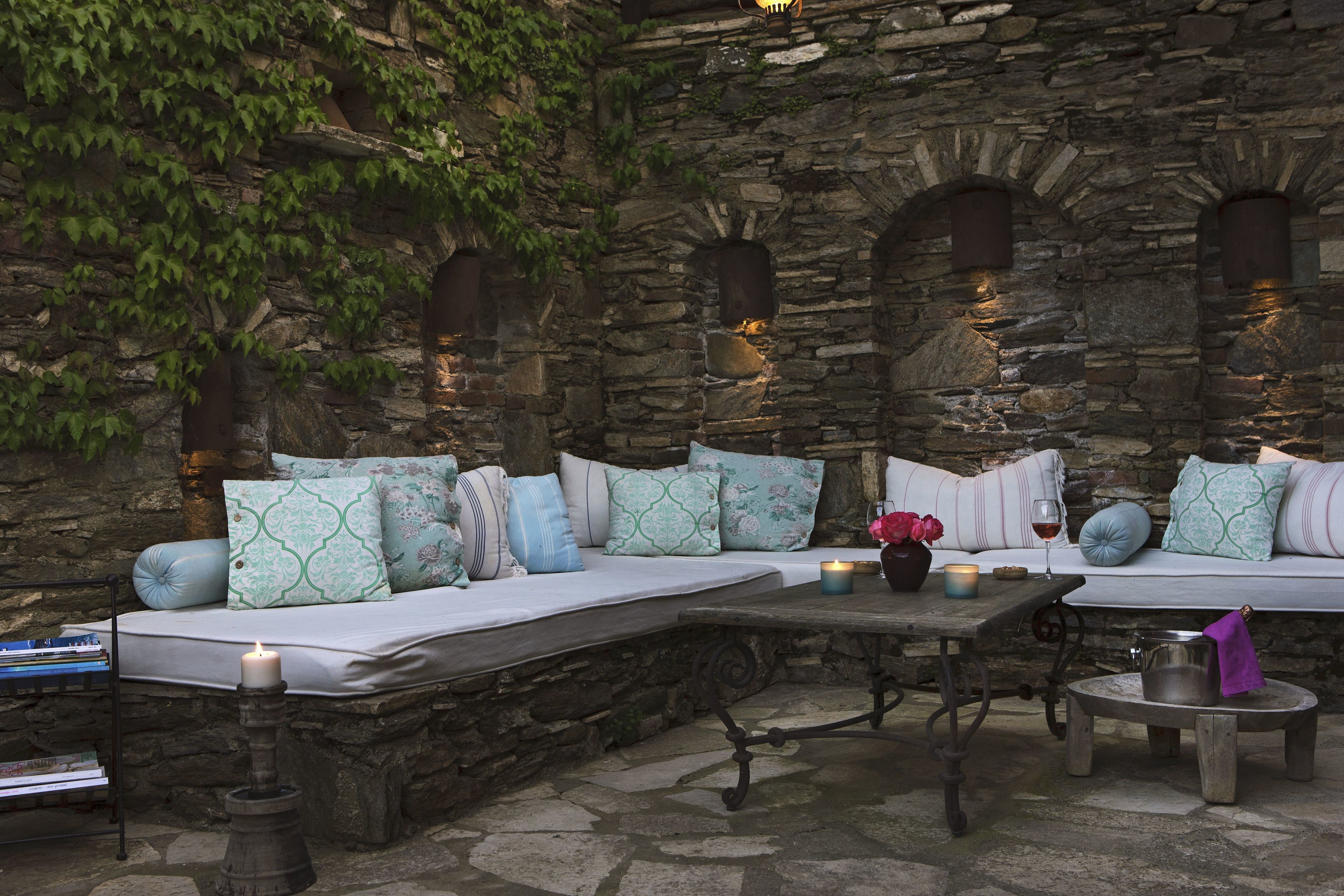 A stone wall with arched windows and a bench with cushions.