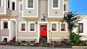 A two-story building with a red door, multiple windows, and potted plants. - 19 Oda Bozcaada (Adults Only) (Bozcaada)