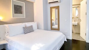 A neatly made bed with white linens and a patterned pillow, a framed picture on the wall, and a mirror above the door. - 19 Oda Bozcaada (Adults Only) (Bozcaada)