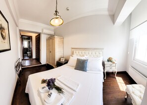 A hotel room with a large bed, a bedside table, a nightstand, a wardrobe, and a bathroom visible through an open door. - 19 Oda Bozcaada (Adults Only) (Bozcaada)