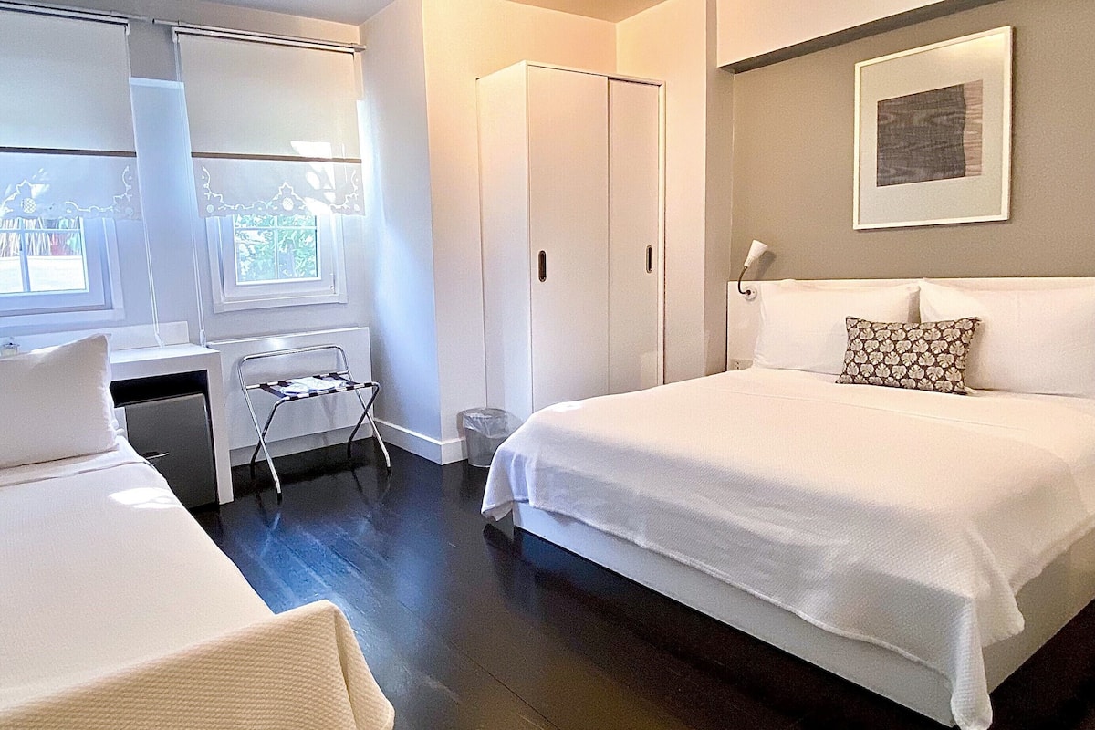 A modern hotel room with a large bed, a desk, and a chair.