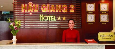 Una recepción de hotel con un letrero que dice "HAU GIANG 2 HOTEL" y relojes en la pared.