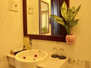 Une salle de bain avec un lavabo, un miroir et une plante en pot.