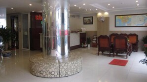 A hotel lobby with a central column, reception desk, seating area, and a map on the wall. - Hau Giang 2 (Can Tho)