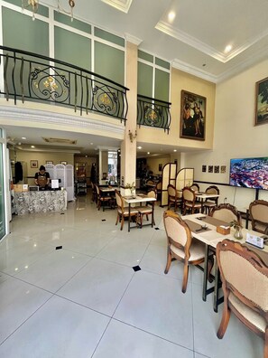 A hotel lobby with a high ceiling, a central staircase, and a dining area with wooden furniture. - Central Hotel and Residences (Ho Chi Minh City)