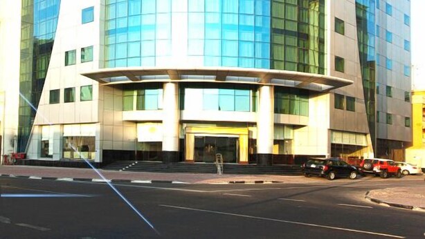 A modern, curved glass building with a prominent entrance and a covered area at the base.