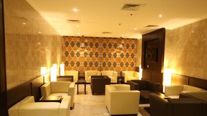 A hotel lobby with seating arrangements, a patterned wall, and ambient lighting.