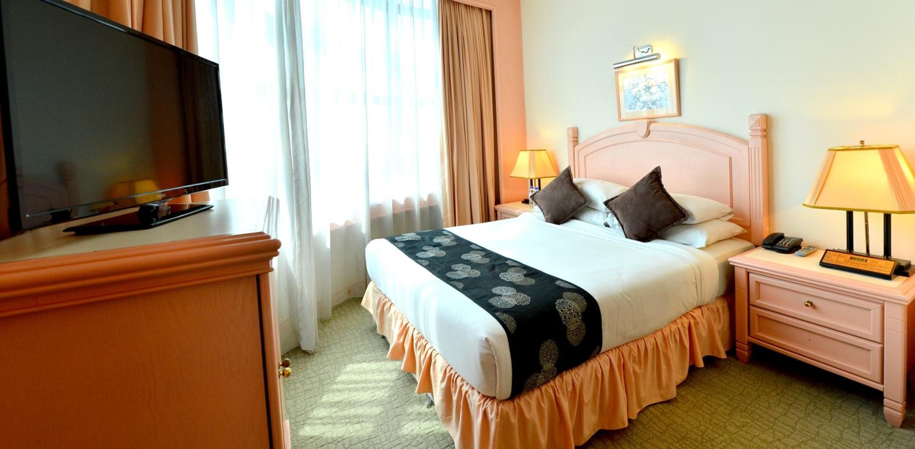 A hotel room with a bed, a television, a bedside lamp, and a nightstand.