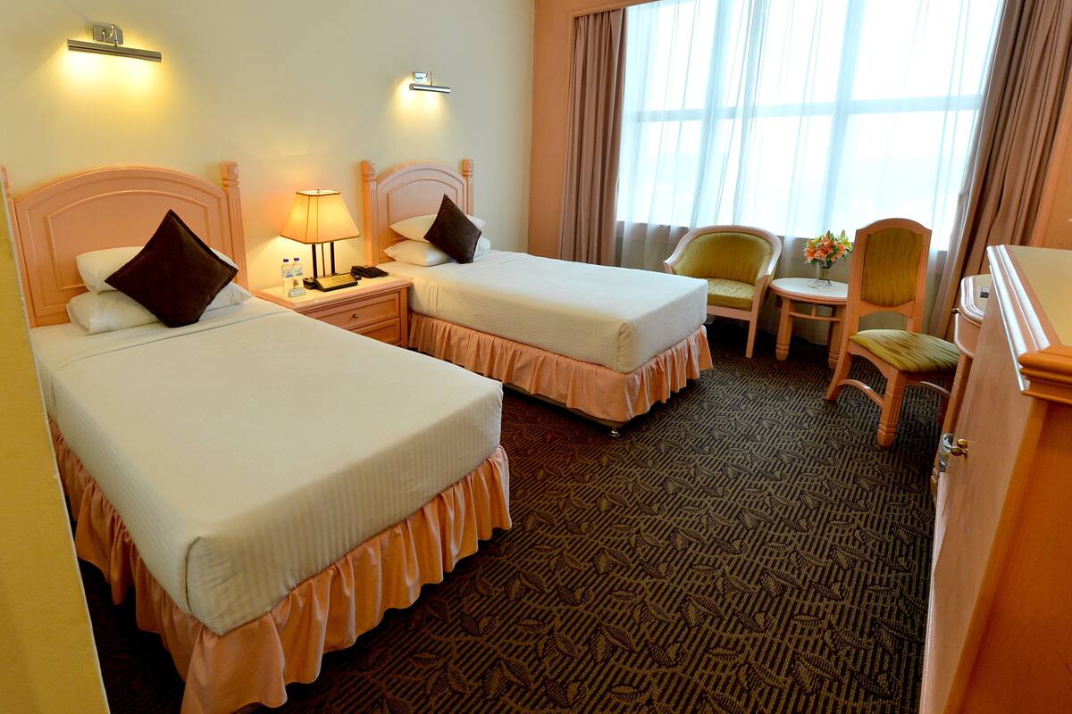 Une chambre d’hôtel avec deux lits, un bureau, une chaise et une petite table.