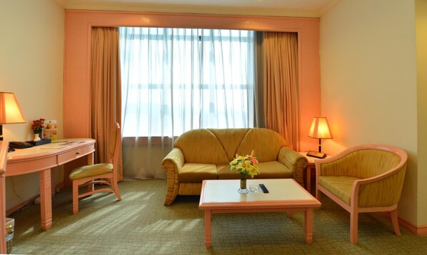 Habitación de hotel con sofá, mesa de centro, escritorio y una silla.