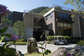 A modern building with a two-story structure, large windows, and a paved entrance area with a golf cart. - Goya Spring Resort (Taichung)
