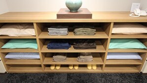 Una habitación de hotel con una cama de madera, una lámpara de noche, un teléfono y ropa doblada ordenadamente en estantes.