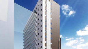 Un hotel moderno con una estructura alta y rectangular, varios pisos y una entrada destacada con puertas de vidrio.