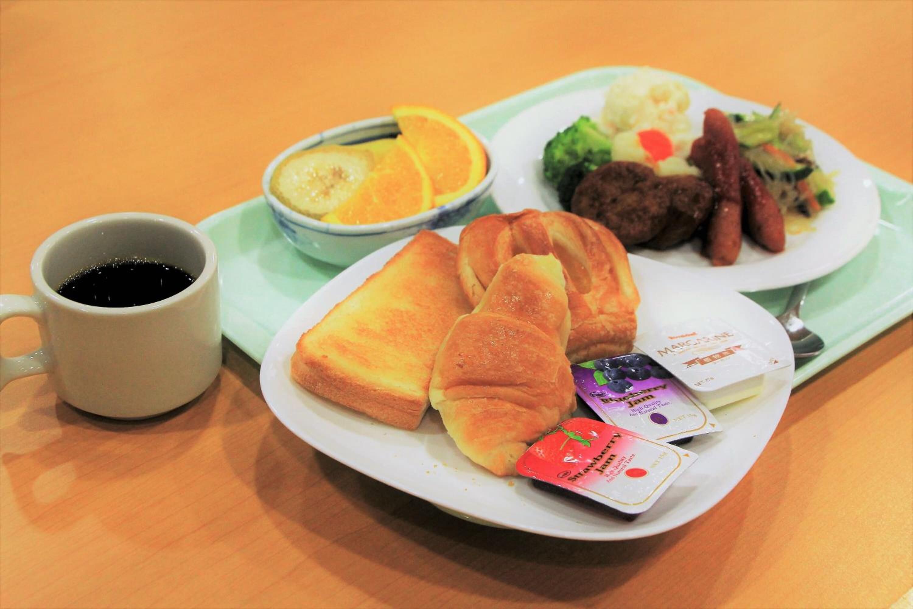 A meal tray with toast, sausage, vegetables, and a cup of coffee.