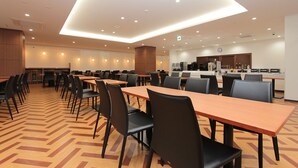 Un comedor amplio con varias mesas y sillas, una cocina equipada y un diseño moderno y elegante.