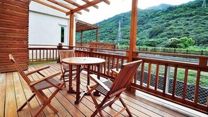 A wooden deck with a table and chairs, overlooking a lush green landscape and a mountain. - Cai Feng B&B (Ji'an)