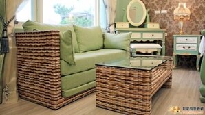 A room with a green sofa, a wicker coffee table, a dresser, and a mirror. - Cai Feng B&B (Ji'an)