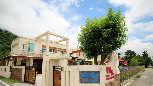 A modern building with a large tree in front, a gated entrance, and a signboard. - Cai Feng B&B (Ji'an)