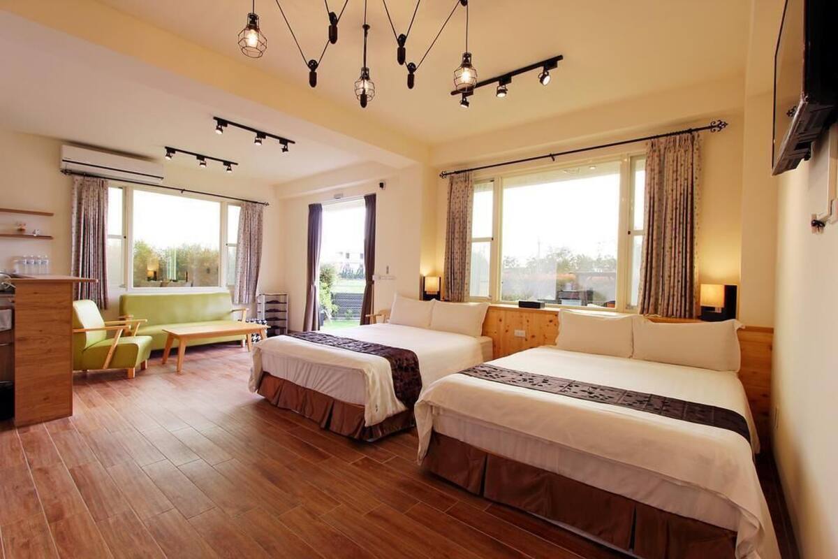 Quarto de hotel com duas camas, um sofá, uma mesa de centro e uma escrivaninha.