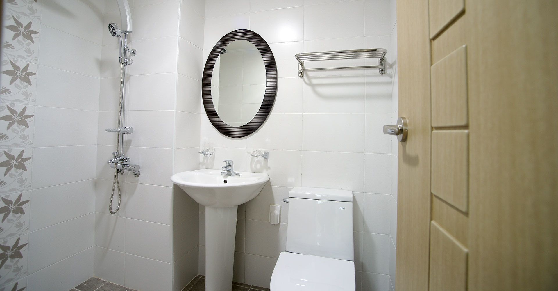 Un baño con ducha, lavabo, inodoro y puerta de madera.