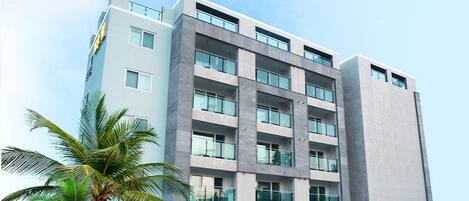 Un hôtel moderne, avec plusieurs étages, de grandes fenêtres et une enseigne indiquant qu’il s’agit d’un complexe hôtelier et d’un centre de bien-être.