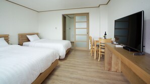 A hotel room with two beds, a wooden desk, a television, and a door leading to another room. - Bowoohill (Seogwipo)