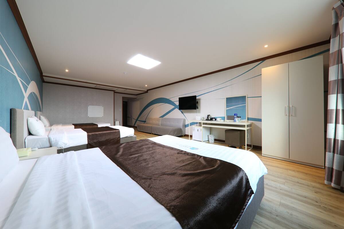 Habitación de hotel con dos camas, un escritorio, un televisor y un armario.