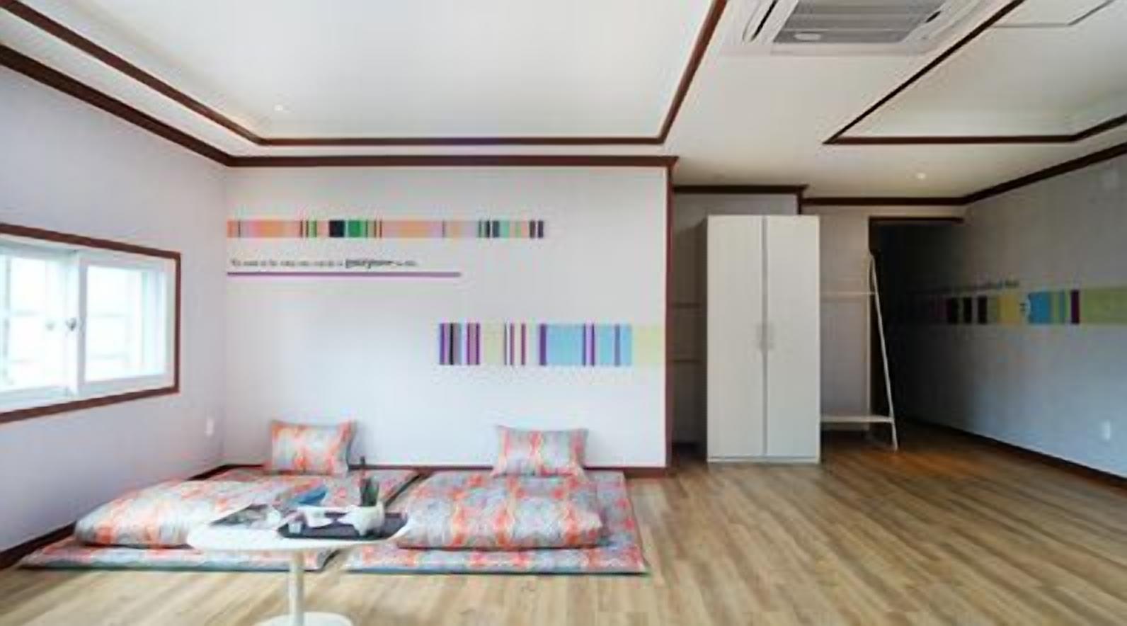 A modern room with a sofa, a cabinet, and a wall with colorful stripes.