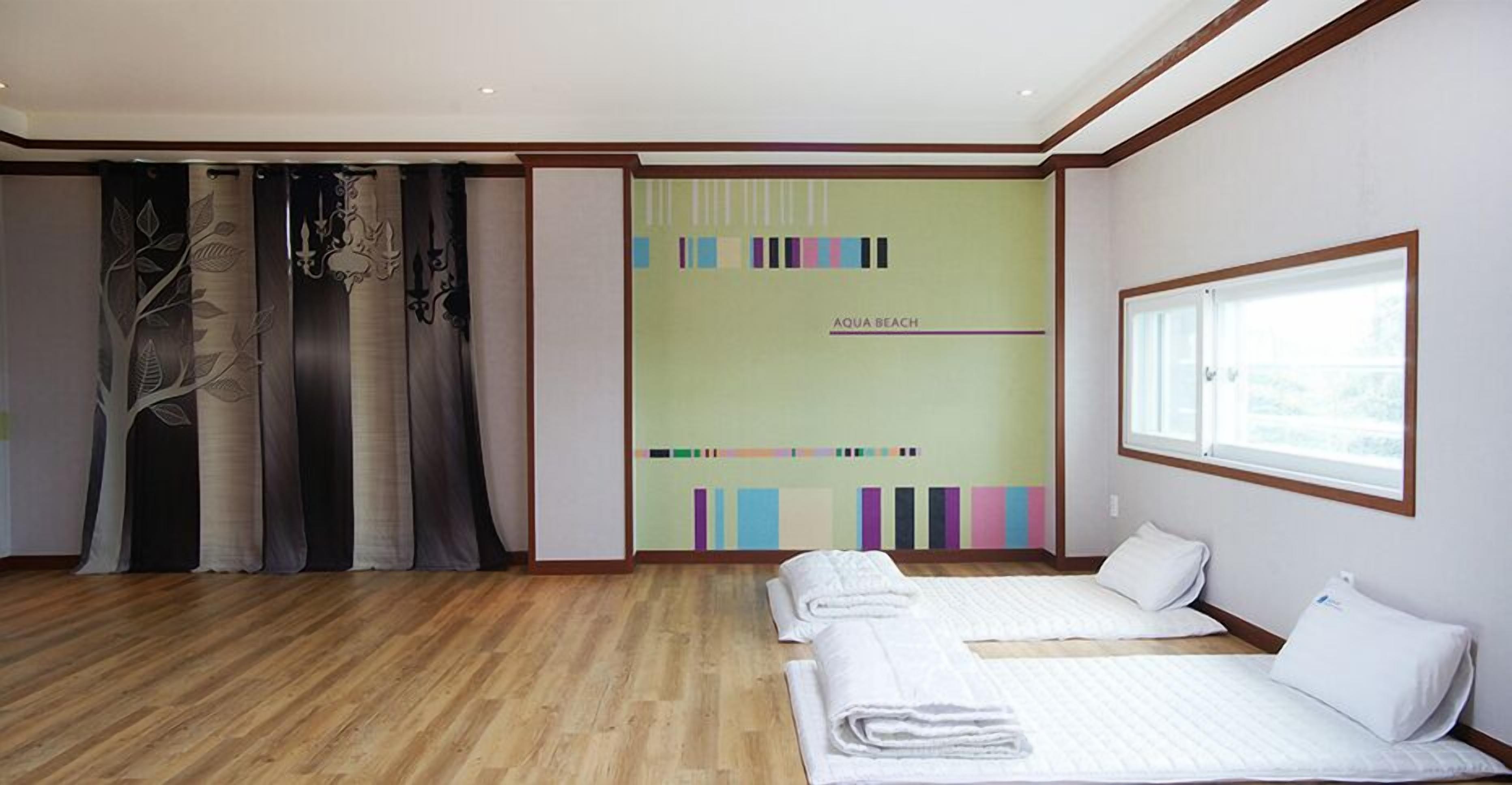 Une chambre d’hôtel avec deux lits, une grande fenêtre et un décor mural aux couleurs vives.