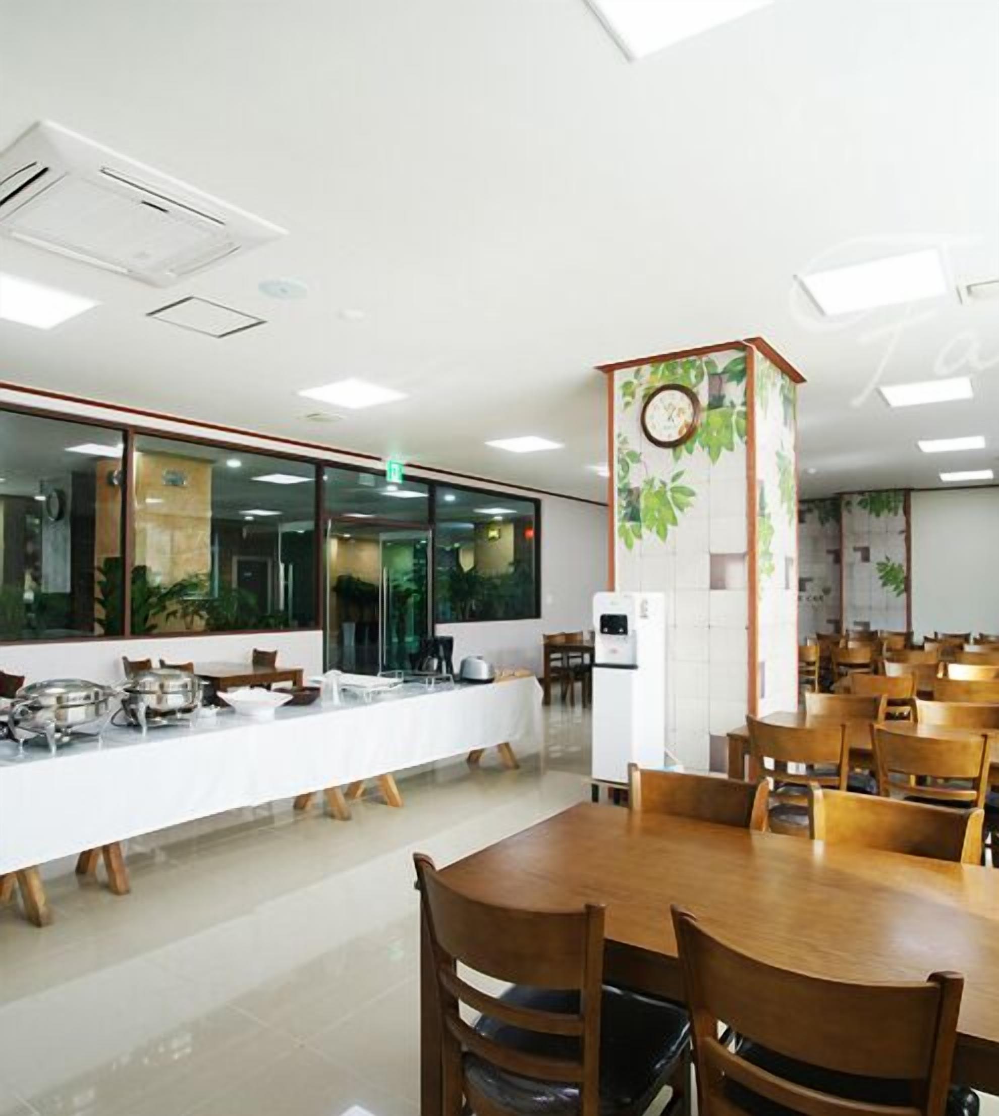 A spacious dining area with multiple tables and chairs, a buffet setup, and a clock on a wall.