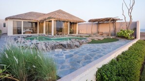 A modern villa with a swimming pool, outdoor seating, and a thatched-roof structure. - Serena Beach Resort (Mandvi)