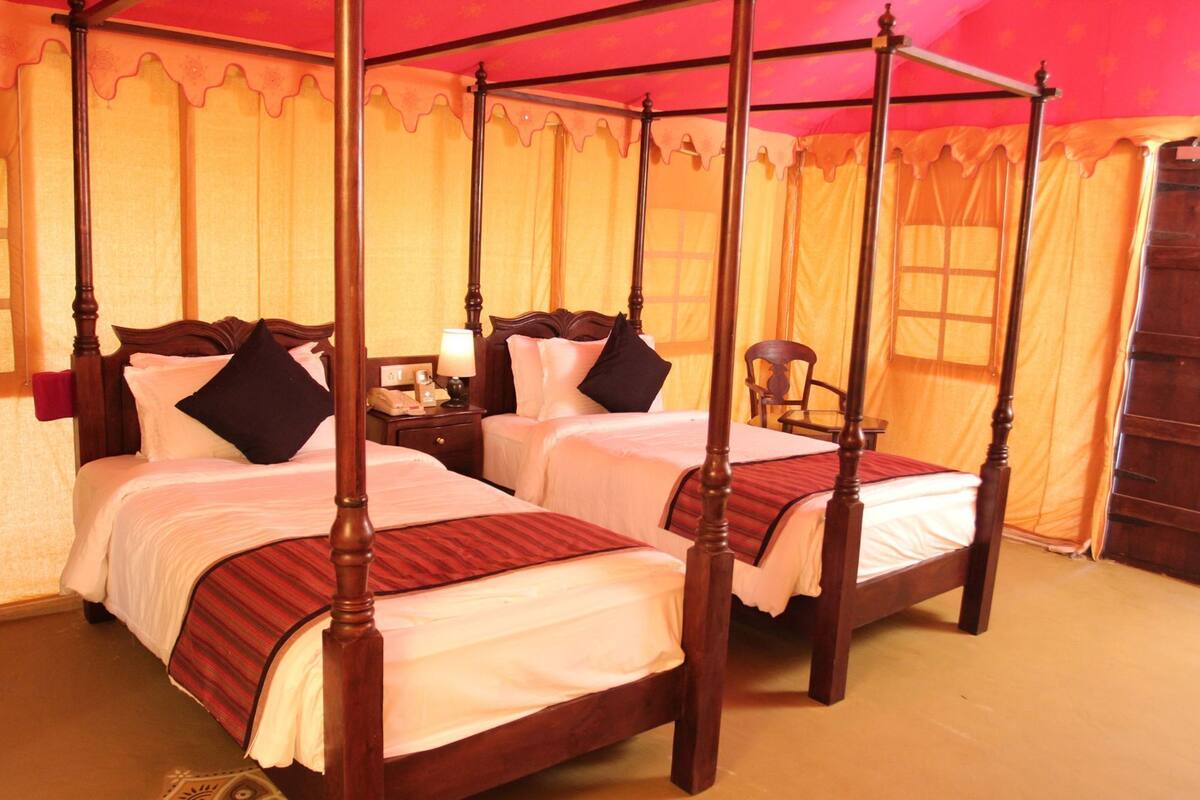 A four-poster bed with a canopy, two bedside tables, and a chair.