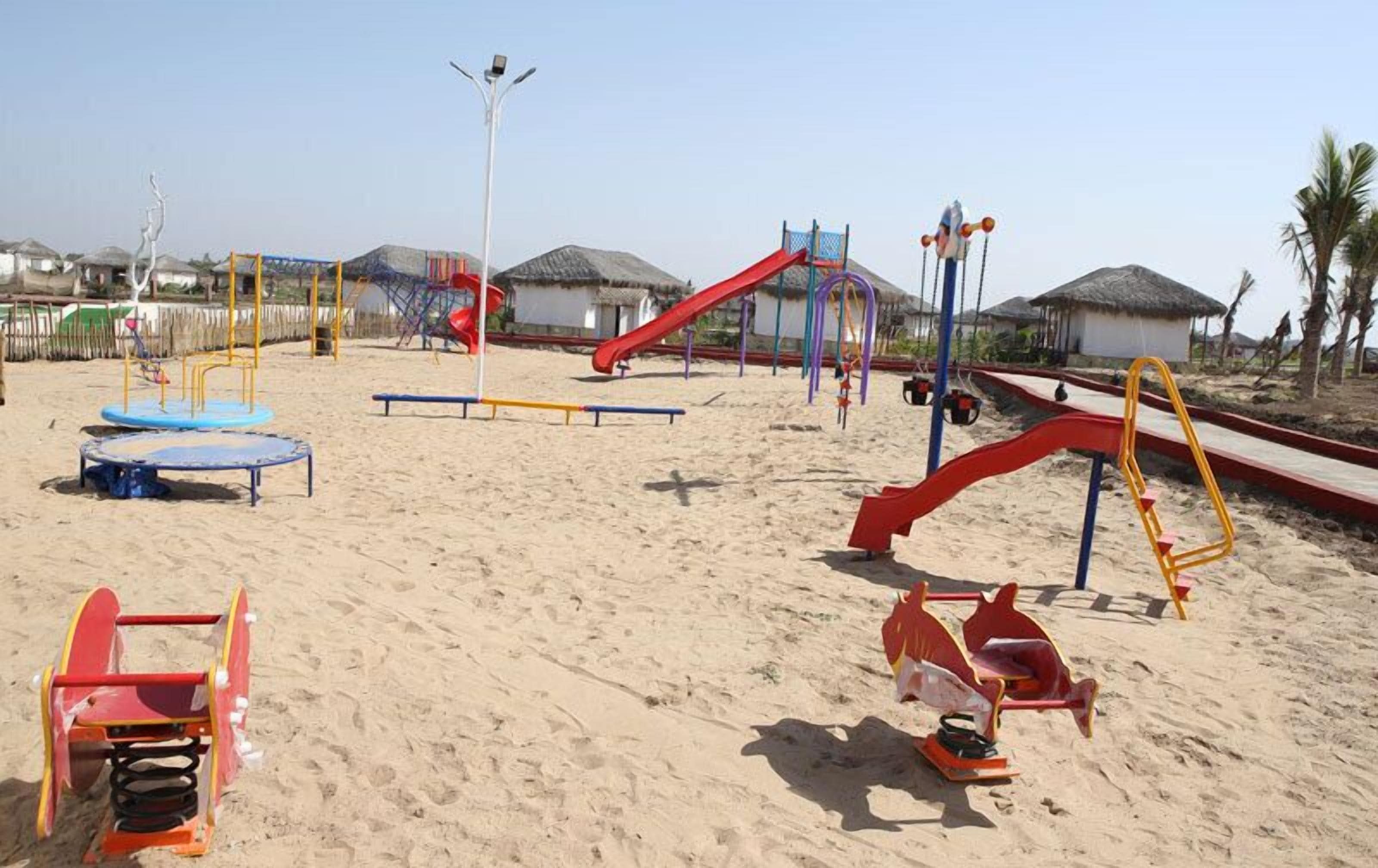 A sandy playground with various play structures including slides and swings.
