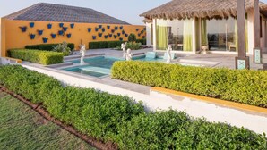 A resort with a swimming pool, a thatched-roof gazebo, and a building with blue planters. - Serena Beach Resort (Mandvi)