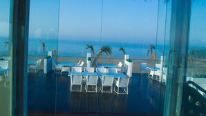 A terrace with white wicker furniture and a view of the ocean. - Serena Beach Resort (Mandvi)