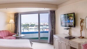 Ein Hotelzimmer mit Bett, Schreibtisch, Stuhl, Fernseher und einem Balkon mit Blick auf die Stadt.
