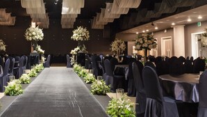 Ein Festsaal mit gedeckten Tischen für eine festliche Veranstaltung, mit einem Mittelgang und floralen Tischdekorationen.