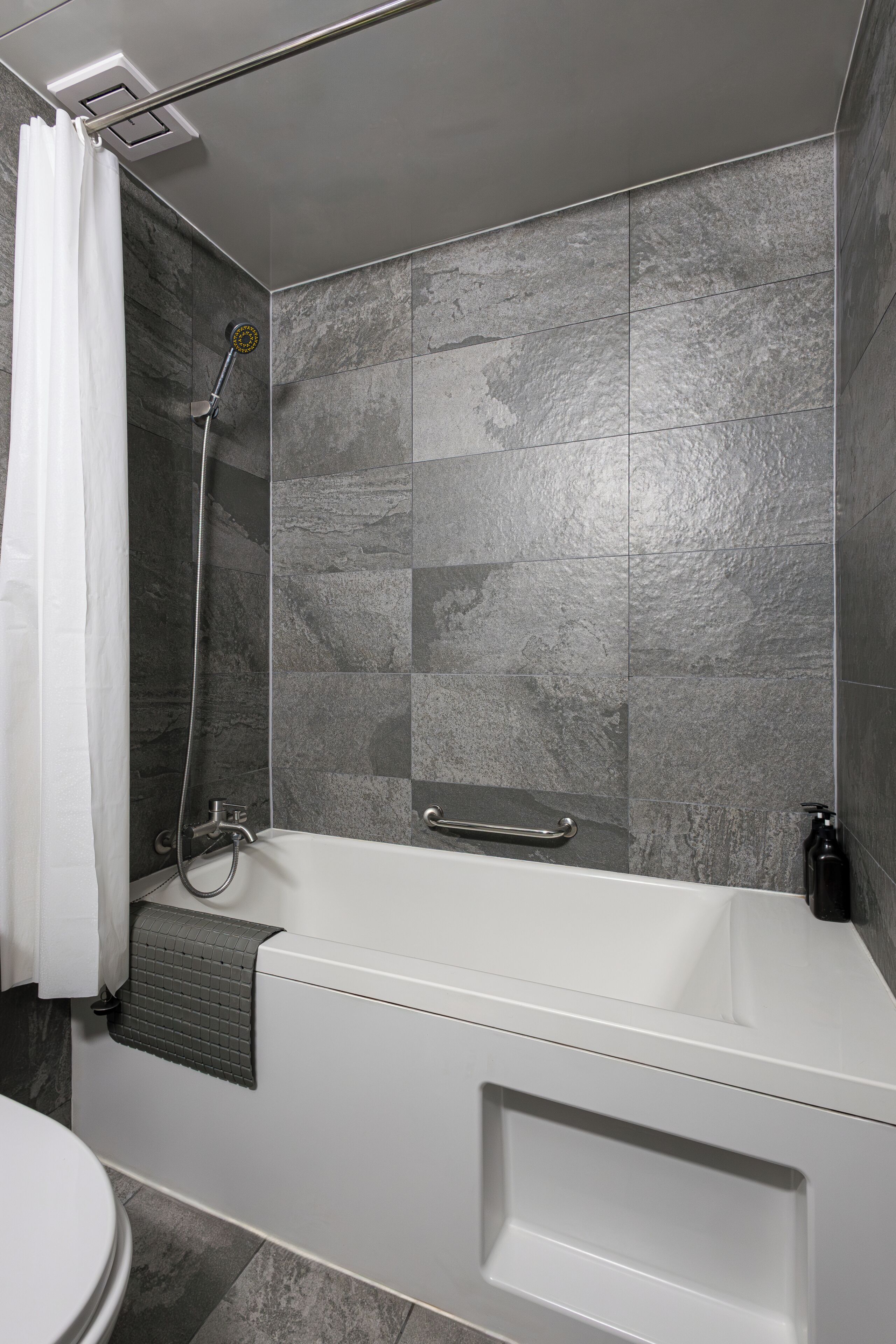 A modern bathroom with a bathtub, shower, and toilet.